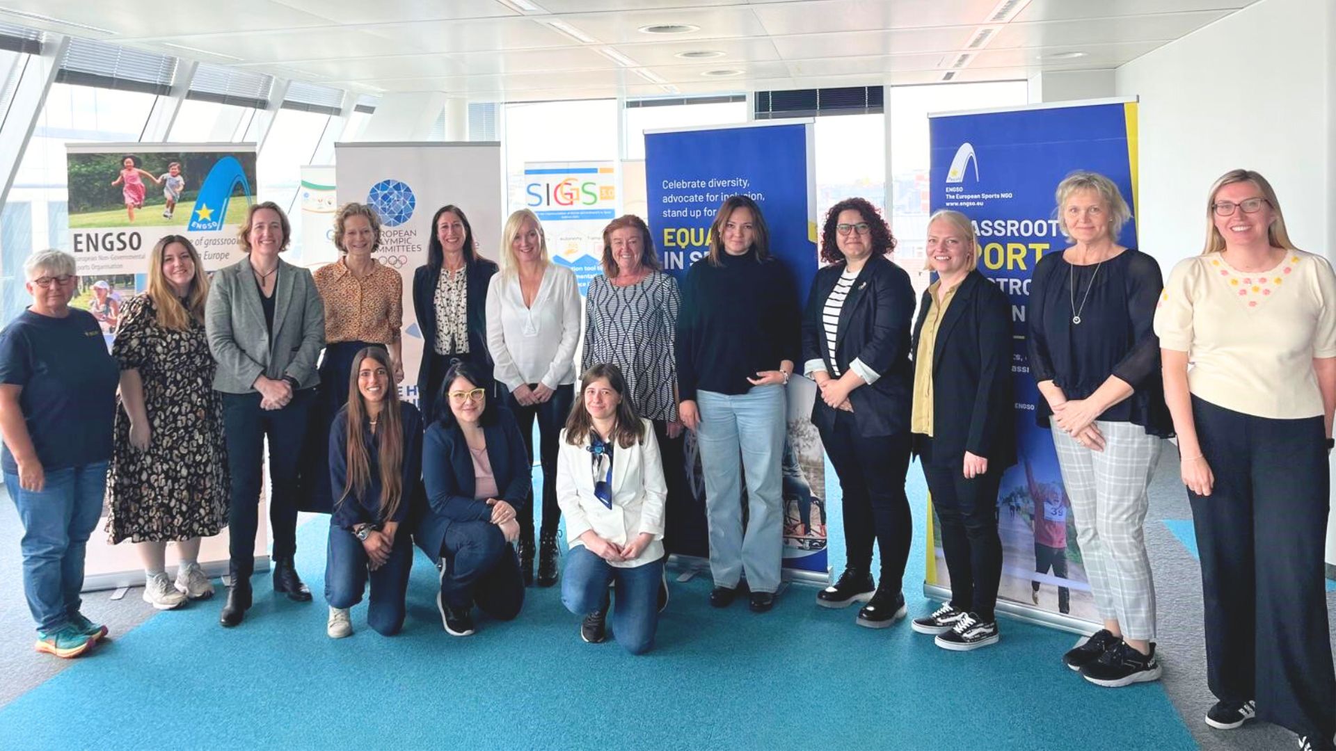 A group of women standing in front of an array of banners, all particpants in the European Summit on Gender Diversity and Equality in Sport