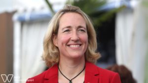 Photograph of IWG Secretary General Lisa O'Keefe MBE, smiling and wearing a red jacket